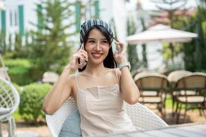 A beautiful Asian woman sits in a beautiful English garden talking on the phone with her friend. photo