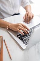 un de cerca imagen de un mujer mecanografía en teclado, trabajando en el computadora a un mesa en un café tienda. foto