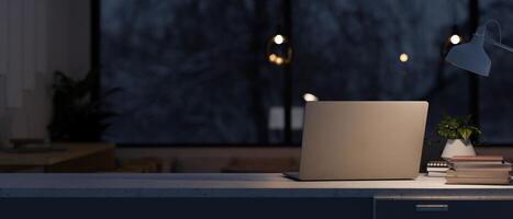 A modern dark office at night features a laptop computer, decor, and a dim light from a table lamp. photo