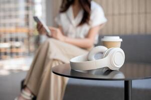 un selectivo atención imagen de un para llevar café taza y auriculares en un café mesa en un café tienda. foto