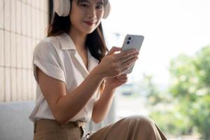 A cropped image of a woman is using her smartphone while listening to music on her headphones. photo