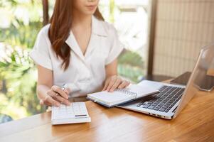 A cropped image of a businesswoman using a calculator, working in the office. photo