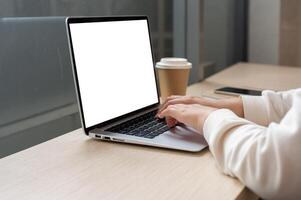 A close-up image of a woman working remotely at a coffee shop, working on her laptop computer. photo