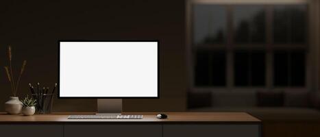 A comfortable home office workspace at night features a computer mockup on a table in the dark room. photo