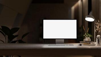 A white-screen computer mockup and a dim light from a lamp on a table in a modern dark office. photo