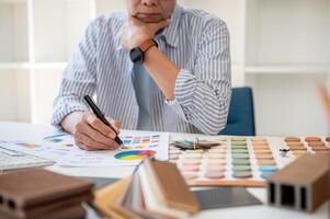 An interior designer working on a project in the office, checking color samples on a swatch palette. photo