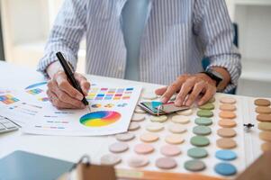 un interior diseñador trabajando en un proyecto en el oficina, comprobación color muestras en un muestra de tela paleta. foto