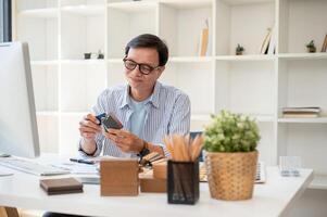 A satisfied senior Asian male interior designer is checking the building material on samples. photo