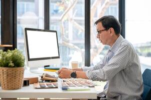 un experimentado asiático masculino interior diseñador o arquitecto es trabajando en su proyecto en el oficina. foto