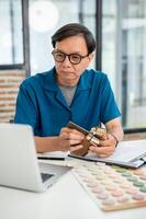 Expert senior Asian male interior designer is checking the building interior design on his computer. photo