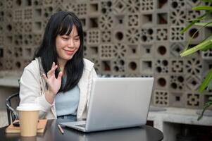 A woman is having an online meeting via her computer while working remotely from a coffee shop. photo