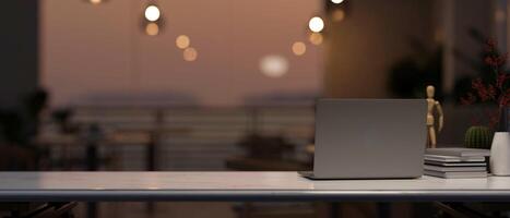 A computer on a tabletop with a blurred background of a beautiful sunset view through the balcony. photo