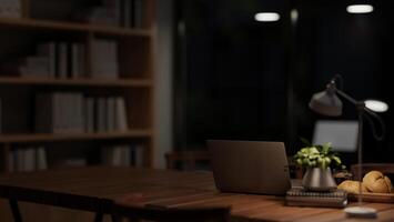 A laptop computer on a meeting table under a dim light from a table lamp in a meeting room at night. photo