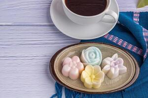 Top view of colorful coconut milk jelly on a plate on a blue cloth with a white coffee cup background. Concept of Thai dessert and beverage photo