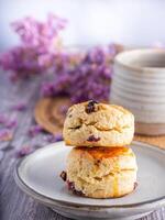 Close-up of traditional British scones placed on a plate with a teacup and flower blurred background. Space for text photo