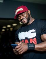 atractivo hermoso hombre en gorra smilling en gimnasia. muscular fuerte masculino descansando en el gimnasia. foto