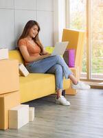 Asian businesswoman is an e-commerce entrepreneur sitting on a chair, smile and are chatting with customers through a laptop in her office. Young woman's wearing casual cloth. Business Concept photo