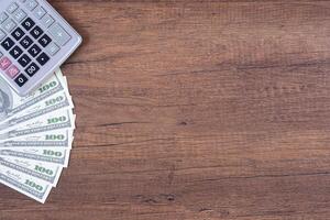 Top view of money US dollars and calculator on wooden table. Space for text. Wood texture background. Business and finance concept photo