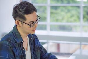 Young man wearing glasses looking away while sitting in the office. Space for text photo