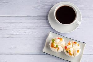 Top view of Thai steamed cupcakes topped with dry fruit on a plate on a blue cloth with a white coffee cup.. photo