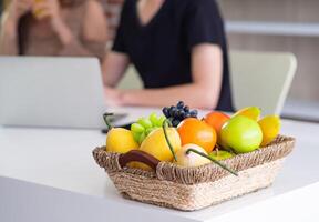 de cerca de frutas en el cesta metido en el mesa con joven Pareja borroso antecedentes foto