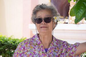 mayor mujer en pie sonrisa debajo el árbol foto