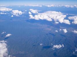 Aerial view of mountains, sky and clouds seen through airplane window photo