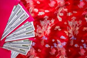 Close-up of red envelopes with money dollars or Ang Pao prepare for given to children in Chinese New Year. Red cloth pattern background and space for text. Festival concept photo