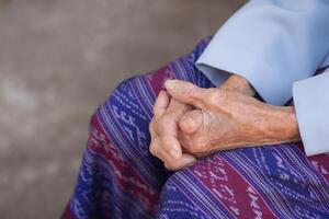 Close-up of hands senior woman joined together while sitting on a chair in a garden. Focus on hands wrinkled skin. Concept of aged people and healthcare photo