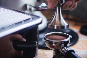 Close-up of hands barista presses ground coffee using a tamper. The process of making coffee step by step photo