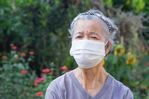 retrato de un mayor mujer con corto blanco cabello, vistiendo un cara máscara para proteger virus, COVID-19, coronavirus, bacterias, polen granos, aire contaminación pm 2.5, y más. cuidado de la salud concepto foto