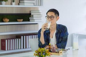 A young man is drinking a fresh glass of milk and breakfast at the workplace. Healthcare concept photo