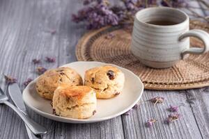 Close-up of traditional British scones and cookies on a plate with a teacup and flower blurred background. Space for text photo