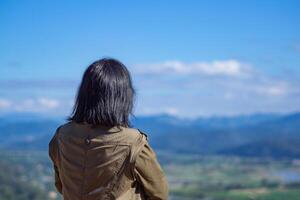 Back view of a woman person stands alone looking at mountains. Travel concept. Back View photo