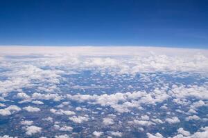 Aerial view of agricultural field, river, and clouds are seen through the airplane window photo