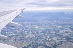 Aerial view of agricultural fields, river, mountains, and land have seen through the airplane window photo