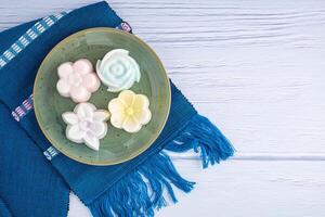 Top view of colorful coconut milk jelly on a plate on a blue cloth. Space for text. Concept of Thai dessert photo