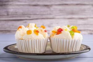 Side view of Thai steamed cupcakes topped with dry fruit on a plate on blue cloth with wooden background. photo