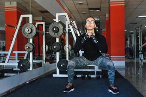 bonito niña haciendo extensión ejercicios en el piso a el gimnasia. foto