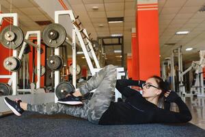 bonito niña haciendo extensión ejercicios en el piso a el gimnasia. foto