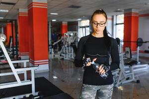 joven mujer Bebiendo agua después haciendo ejercicio aptitud gimnasio foto