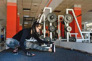 Beautiful slim brunette doing some stretching exercises in a gym photo