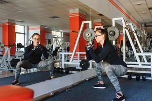 bonito niña haciendo extensión ejercicios en el piso a el gimnasia. foto