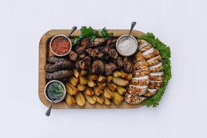 Most meat dish - beef kebabs, sausages, grilled mushrooms, potatoes, tomatoes and sauce. The best choice for a beer. Close-up on a white background photo