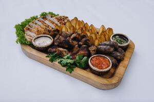 Most meat dish - beef kebabs, sausages, grilled mushrooms, potatoes, tomatoes and sauce. The best choice for a beer. Close-up on a white background photo