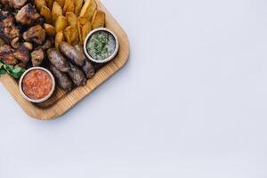 Most meat dish - beef kebabs, sausages, grilled mushrooms, potatoes, tomatoes and sauce. The best choice for a beer. Close-up on a white background photo