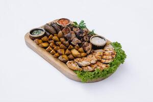 Most meat dish - beef kebabs, sausages, grilled mushrooms, potatoes, tomatoes and sauce. The best choice for a beer. Close-up on a white background photo