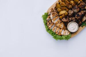 Most meat dish - beef kebabs, sausages, grilled mushrooms, potatoes, tomatoes and sauce. The best choice for a beer. Close-up on a white background photo