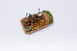 Most meat dish - beef kebabs, sausages, grilled mushrooms, potatoes, tomatoes and sauce. The best choice for a beer. Close-up on a white background photo