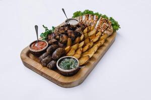 Most meat dish - beef kebabs, sausages, grilled mushrooms, potatoes, tomatoes and sauce. The best choice for a beer. Close-up on a white background photo